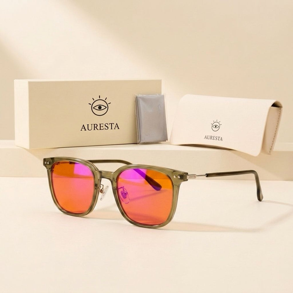 Olive blue light glasses with orange lenses beside the Auresta box, folding case and cleaning cloth