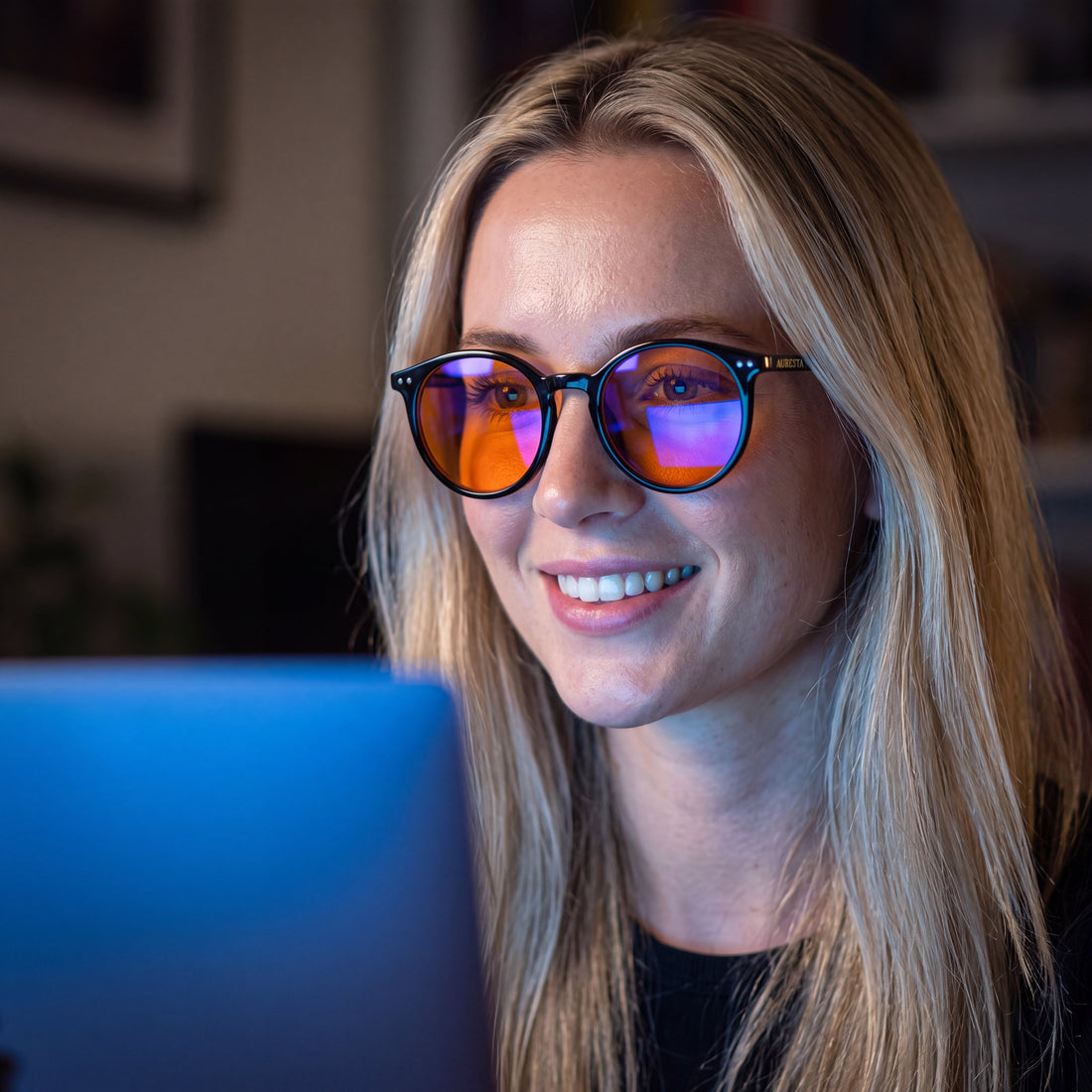 Auresta Raven blue light glasses — round black acetate with amber lenses, worn while working at a laptop