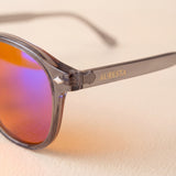 Close-up of the Aura blue light glasses — gold AURESTA lettering on the grey translucent TR90 temple and orange orange lens
