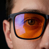Macro detail of one Ember lens, orange tint over the eye with a pixel grid reflected on the glass