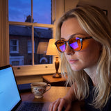 Close-up of Hazel round tortoise TR90 blue light glasses with orange lenses during evening laptop work