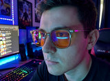 Close-up of a gamer wearing Olive blue light glasses at a neon-lit desk, orange lenses catching screen glow
