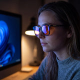 Woman at a monitor at night in the Rowan blue light glasses — glossy black panto TR90 frame, orange lenses