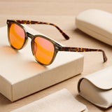 Willow olive round blue light glasses with orange lenses and tortoiseshell temples resting on the Auresta box beside the case
