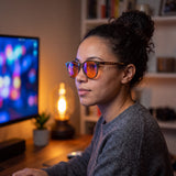 Woman wearing the Willow blue light glasses at her desk in the evening, orange lenses