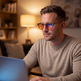 Man wearing the Willow olive round blue light glasses while working on a laptop at night under a warm lamp